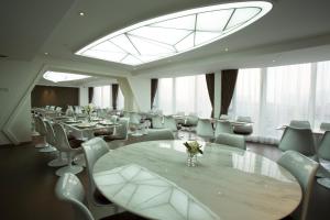 una sala da pranzo con tavoli, sedie e una grande finestra di Guangzhou Planet Hotel a Canton