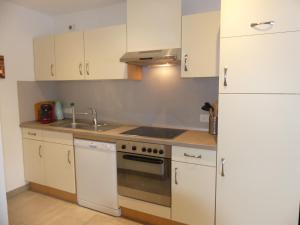 a kitchen with white cabinets and a stove and a refrigerator at Apartment Stefanie by Interhome in Taxenbach