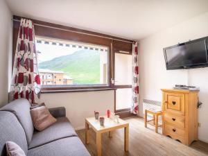 ein Wohnzimmer mit einem Sofa und einem großen Fenster in der Unterkunft Apartment Les Asters-30 by Interhome in Les Menuires