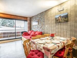 a dining room with a table and a red couch at Apartment Burons R05 by Interhome in Les Menuires
