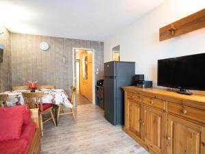 a living room with a flat screen tv and a kitchen at Apartment Burons R05 by Interhome in Les Menuires