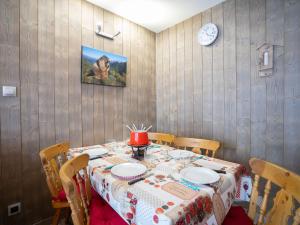 a dining room table with plates and a clock on the wall at Apartment Burons R05 by Interhome in Les Menuires +21 photos