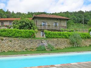 dom za kamienną ścianą obok basenu w obiekcie Holiday Home Casetta by Interhome w mieście Cortemilia