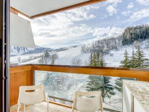 a balcony with two chairs and a view of a snowy mountain at Studio Soyouz Vanguard-69 by Interhome in Le Corbier