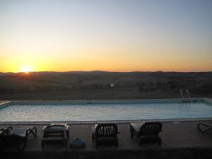 een zwembad met stoelen en de zonsondergang op de achtergrond bij Apartment A1 by Interhome in Casetta