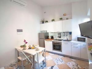 cocina con armarios blancos, mesa y fregadero en Apartment Bufalini 2 - Raffaello by Interhome, en Florencia