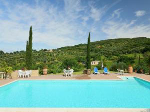 a swimming pool with tables and chairs and a mountain at Holiday Home Poggio Velluto by Interhome in Seggiano