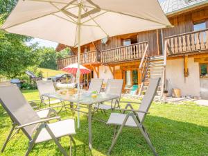 a table and chairs with an umbrella in front of a house at Apartment La Cascade in Saint-Pancrace