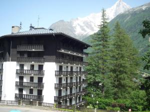 a building with a tree in front of a mountain at Apartment Les Aiguilles du Brévent by Interhome in Chamonix-Mont-Blanc