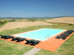 a swimming pool with a bunch of chairs around it at Apartment B1 by Interhome in Casetta