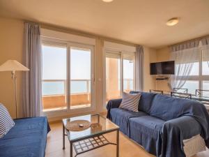 a living room with a blue couch and some windows at Apartment Punta Cormoran by Interhome in La Manga del Mar Menor