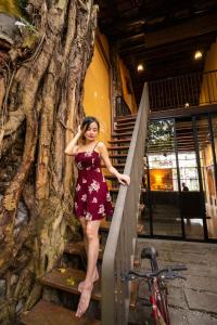 a woman in a dress standing next to a tree at Spices Hotel in George Town