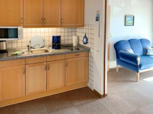 a kitchen with a sink and a blue chair at Apartment Dehne-3 by Interhome in Norddeich