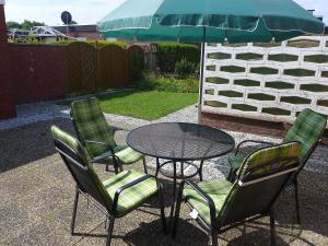 a table with four chairs and a table with an umbrella at Holiday Home Sonnenschein by Interhome in Norddeich