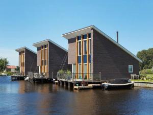 een groot gebouw op het water met een boot erop bij Villa Krekt Oer 't Wetter by Interhome in Uitwellingerga
