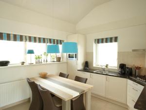 a kitchen with a wooden table and some windows at Villa Krekt Oer 't Wetter by Interhome in Uitwellingerga