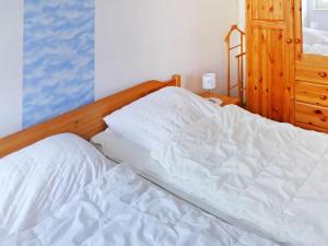 an unmade bed in a bedroom with a wooden headboard at Holiday Home Gila by Interhome in Dornumersiel