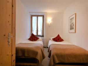 Habitación con 2 camas con almohadas rojas. en Apartment Chesa Corvatsch by Interhome en Pontresina