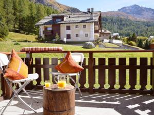 a balcony with two chairs and two glasses of orange juice at Apartment Chesa Linaria by Interhome in Surlej