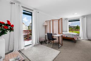 1 dormitorio con 1 cama y escritorio con mesa y ventana en Harbourside Haven - Whangaparāoa Studio Apartment, en Te Whanga