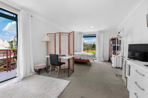 a white room with a bedroom and a bed and a table at Harbourside Haven - Whangaparāoa Studio Apartment in Te Whanga