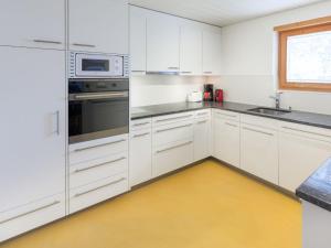 グリンデルワルトにあるApartment Chalet Abendrot-28 by Interhomeの黄色の床のキッチン(白いキャビネット付)