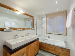 a bathroom with a sink and a tub and a mirror at Apartment Rütschi-7 by Interhome in Zermatt