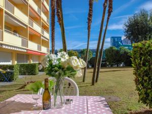 een tafel met een fles wijn en een vaas met bloemen bij Apartment Residenza Lido-1 by Interhome in Locarno