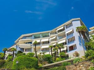 an apartment building with palm trees in front of a blue sky at Apartment Suite Classic-15 by Interhome in Ascona