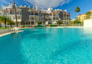 una gran piscina frente a un edificio en Apartamento Victoria Playa III con una gran terraza, en Denia