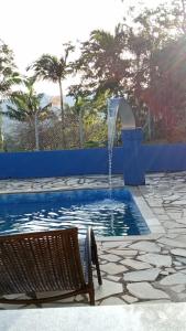 a swimming pool with a fountain with a chair next to it at Pousada do Sossego in Extrema