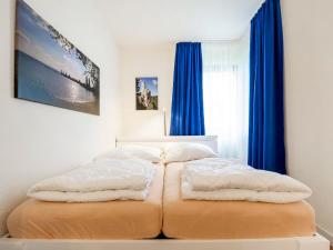 two beds in a bedroom with blue curtains at Apartment Ferienwohnpark Immenstaad-3 by Interhome in Immenstaad am Bodensee +11 photos