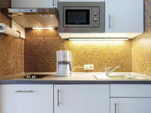 a kitchen with white cabinets and a microwave at Apartment Ferienwohnpark Immenstaad-3 by Interhome in Immenstaad am Bodensee