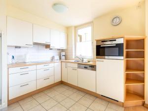 a kitchen with white cabinets and a clock on the wall at Apartment Ferienwohnpark Immenstaad-1 by Interhome in Immenstaad am Bodensee