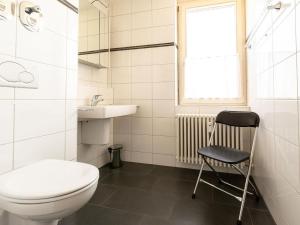 ein Badezimmer mit einem WC, einem Waschbecken und einem Stuhl in der Unterkunft Apartment Ferienwohnpark Immenstaad-1 by Interhome in Immenstaad am Bodensee