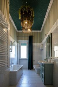 un bagno con lampadario pendente, vasca e lavandino di Alloggi Villa Sarsina ad Anzio