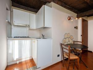 オルタ・サン・ジューリオにあるApartment Mansarda by Interhomeの白いキャビネット、テーブルと椅子付きのキッチンが備わります。