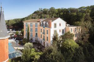 a building with a mountain in the background at Hôtel Spa Thermalia in Châtel-Guyon