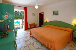 a bedroom with a bed with an orange bedspread at Hotel Park Calitto in Ischia