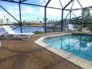 una piscina con 2 sillas de césped y una piscina en Villa Marco Island, en Marco Island