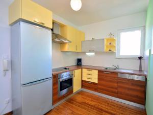 a kitchen with a white refrigerator and wooden cabinets at Apartment Cvita-1 by Interhome in Sovlje