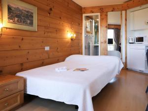 ヴィラール・シュル・オロンにあるApartment Le Bristol A16 by Interhomeの木製の壁に白いベッドが備わるベッドルーム1室