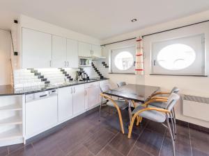 a kitchen with white cabinets and a table and chairs at Apartment Blutsyde Promenade-17 by Interhome in Mispelburg