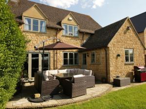 a house with a patio with couches and an umbrella at Woodside Cottage in Chipping Campden