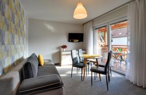 a living room with a couch and a table with chairs at MATTEO Pensjonat Apartamenty in Duszniki Zdrój