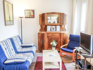 een woonkamer met een blauwe bank en een tv bij Apartment Beauchesne by Interhome in Saint-Malo