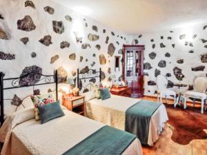 a bedroom with two beds and a rock wall at Holiday Home Titi in Fuencaliente de la Palma