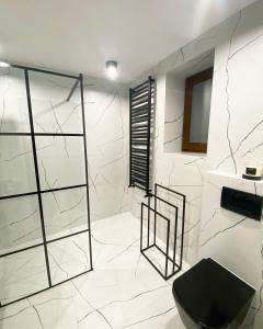 a bathroom with a black toilet and white marble walls at Dom Malowy Sad in Zalesie