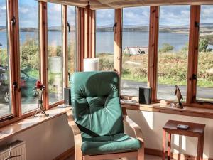a green chair sitting in a room with windows at Holiday Home Fiskavaig by Interhome in Fiskavaig