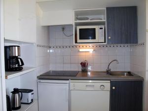 a small kitchen with a sink and a microwave at Apartment les Goelands by Interhome in Mimizan-Plage